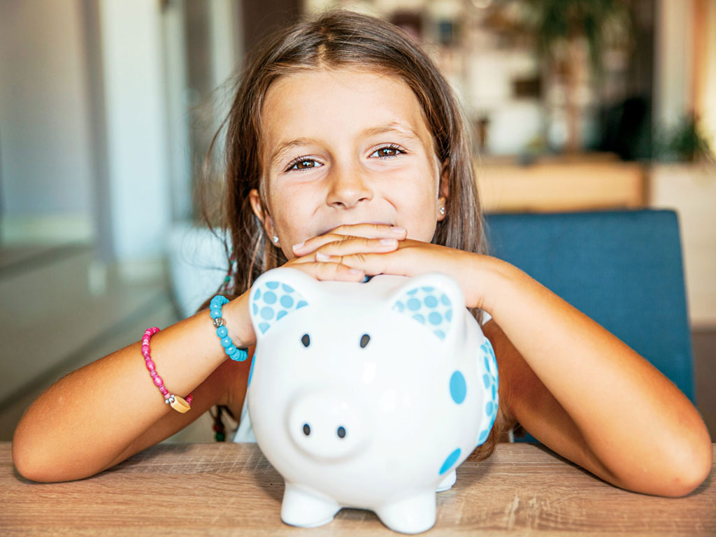little girl smiling over her piggy bank