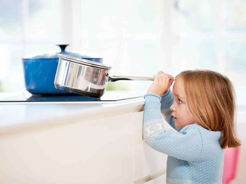 young girl risking accident with pan in kitchen