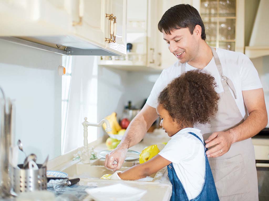 dad teaching his daughter how to wash dishes