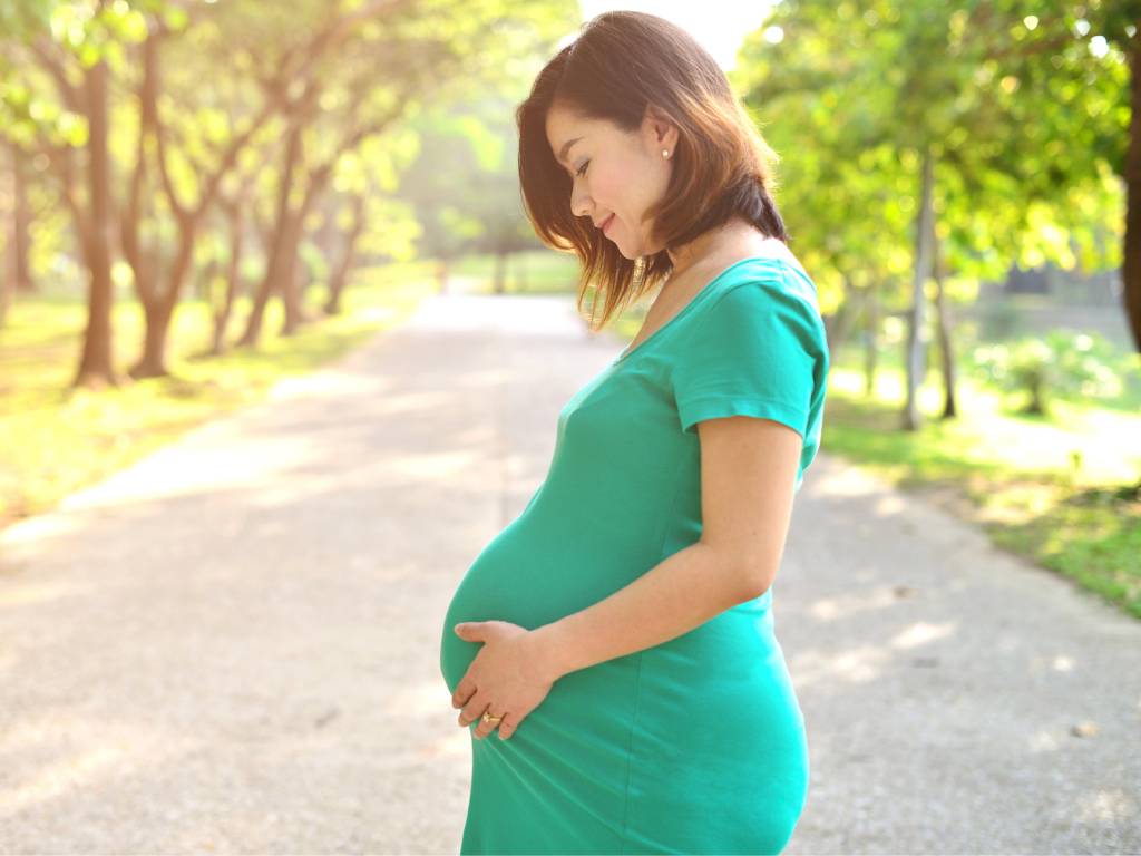 a pregnant woman in a green dress looking at her belly