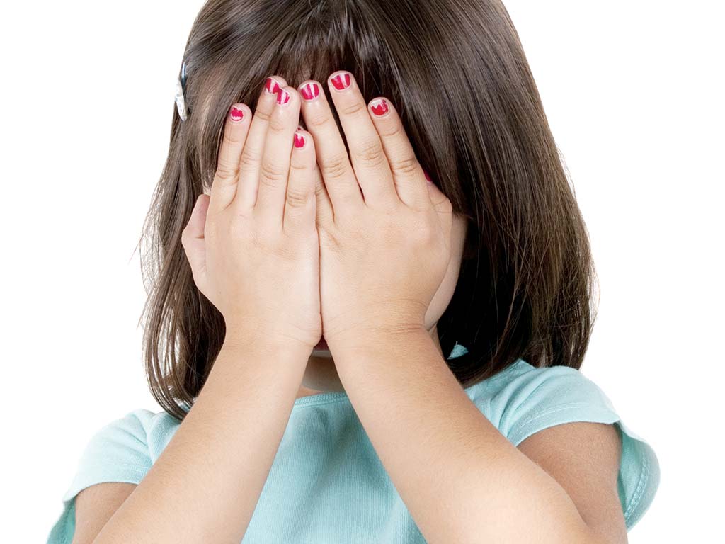 young girl hiding her face with her hands