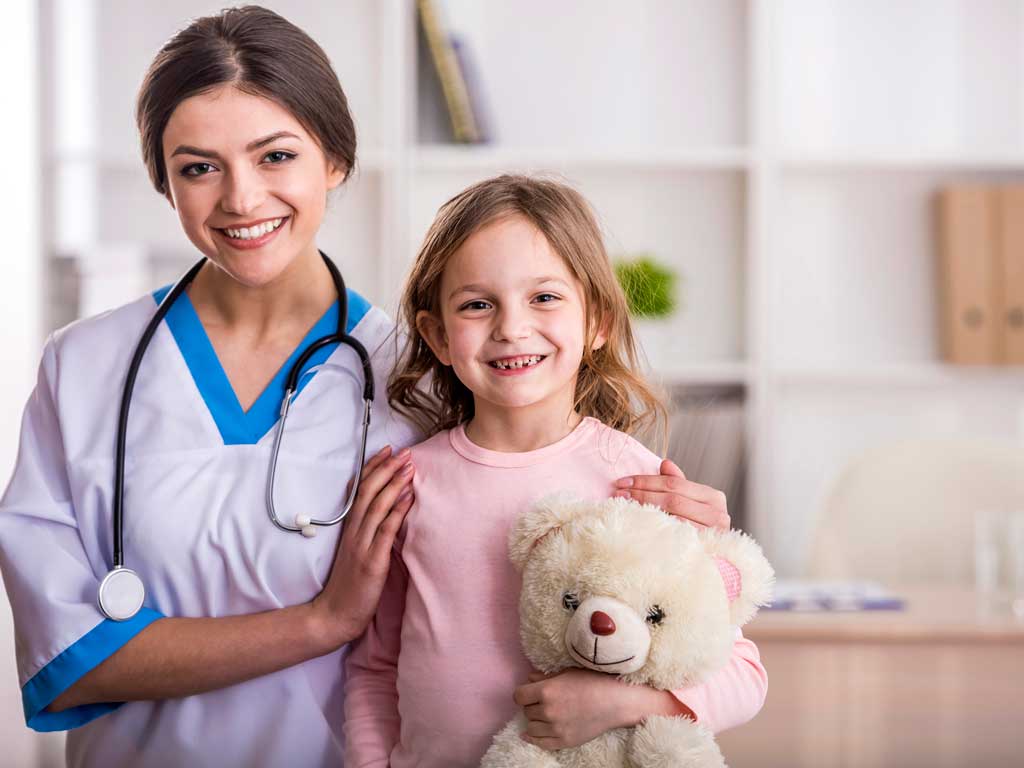 a doctor standing next to a young girl holding a teddy bear