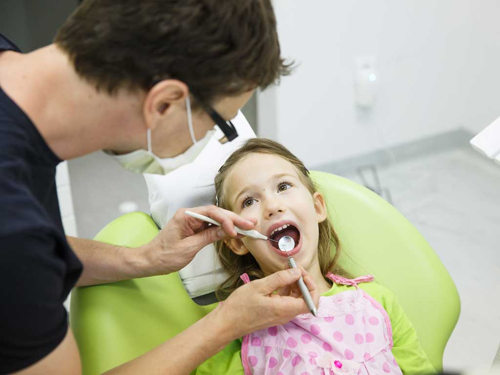 a young girl having her teeth checked by the dentist