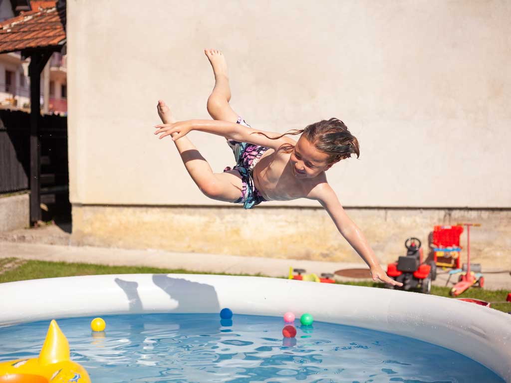 boy jumping into an inflatable swimming pool