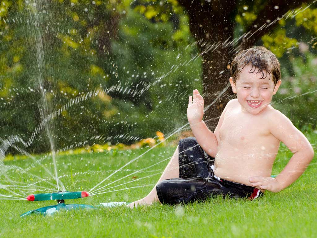 young boy playing with sprinklers