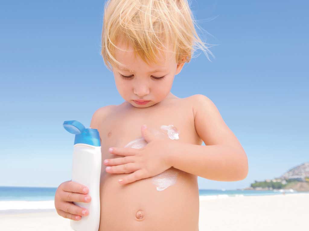 child applying sunscreen on himself