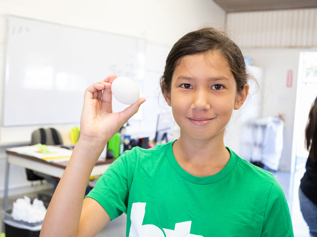 student proudly holding up an egg