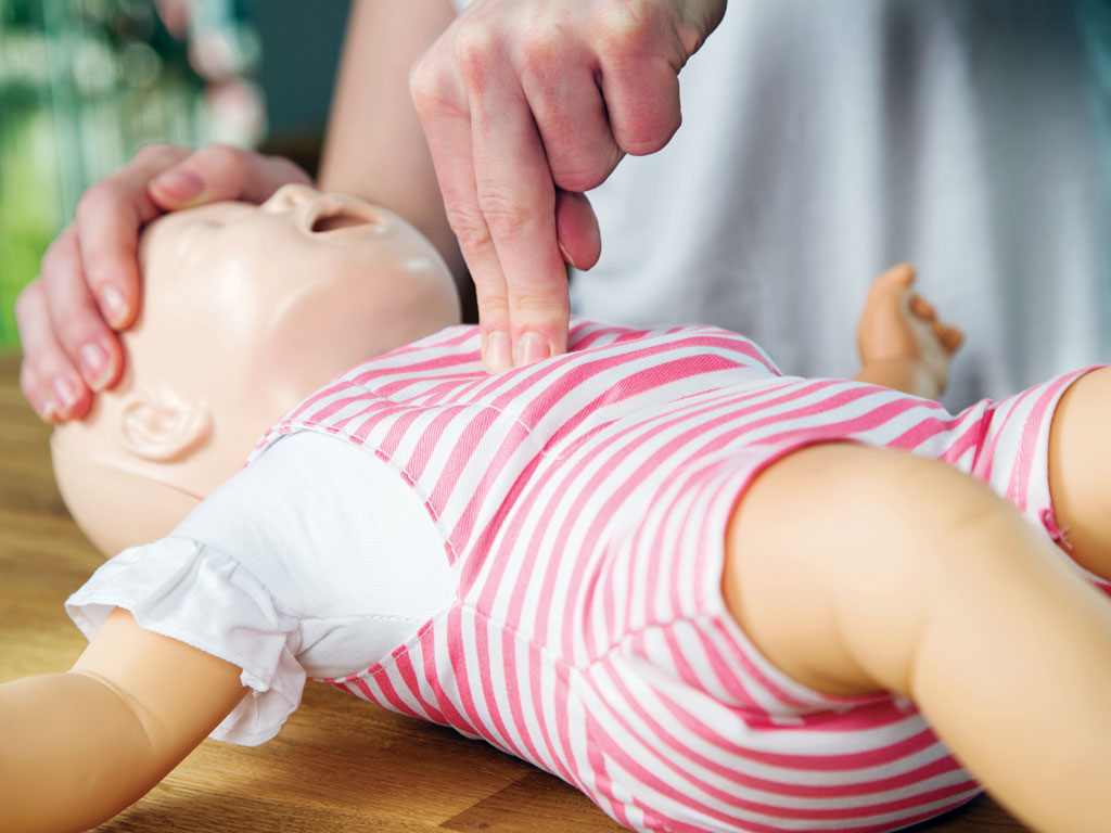 person learning to perform cpr on a infant mannequin
