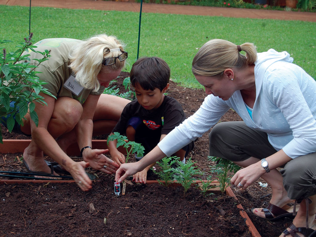 two female adults gardening with a male child