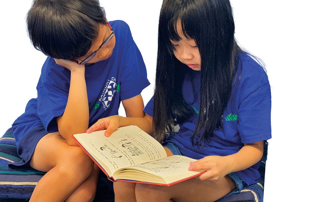 elementary age boy and girl reading a book together