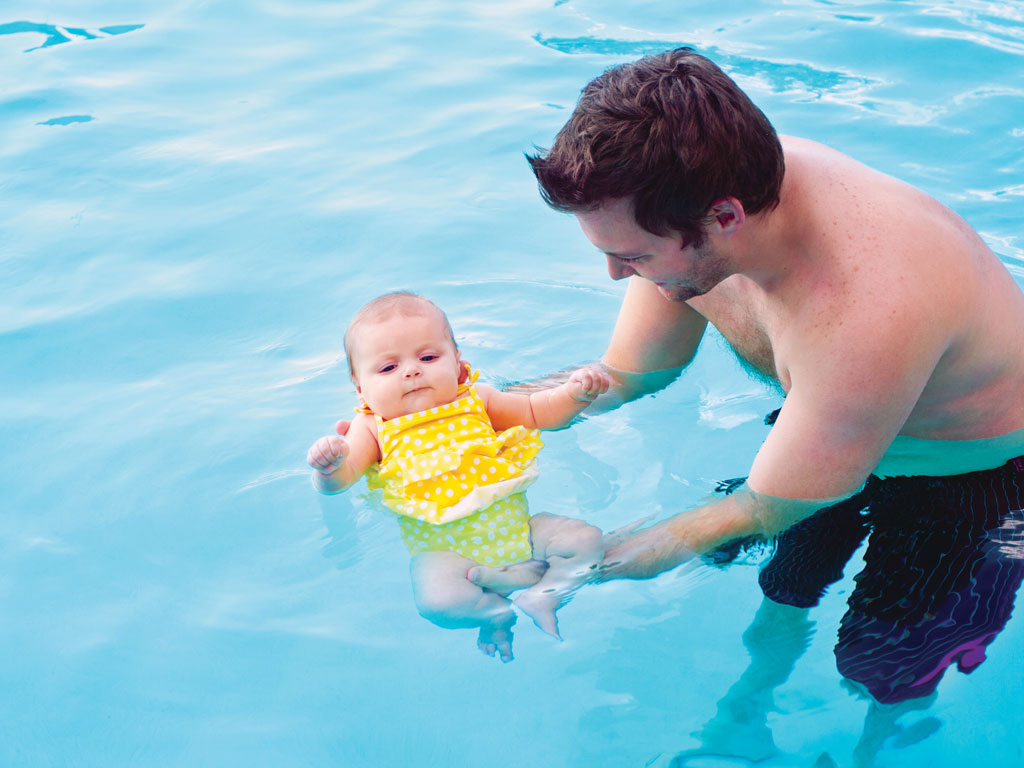dad teaching infant how to swim
