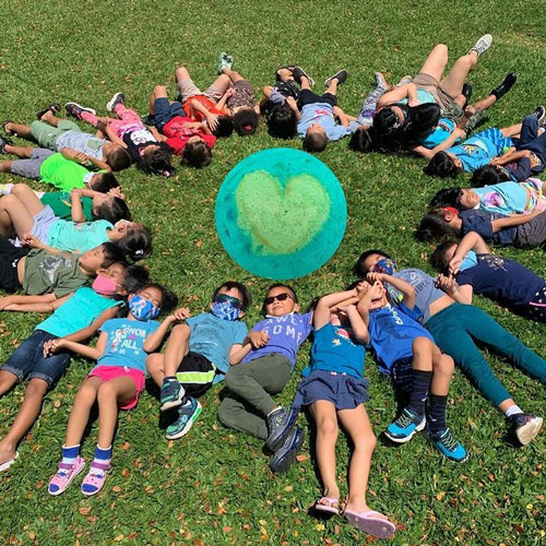preschool age children lying in the grass forming a circle