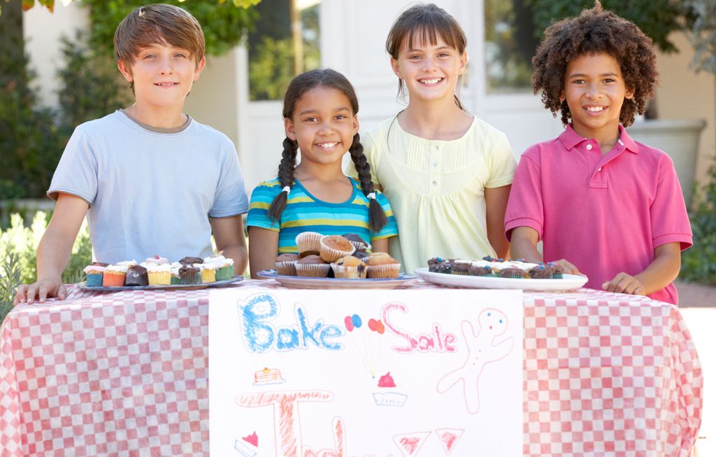 kids smiling at their bake sale table