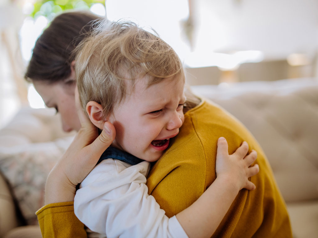 child crying while being held by parent