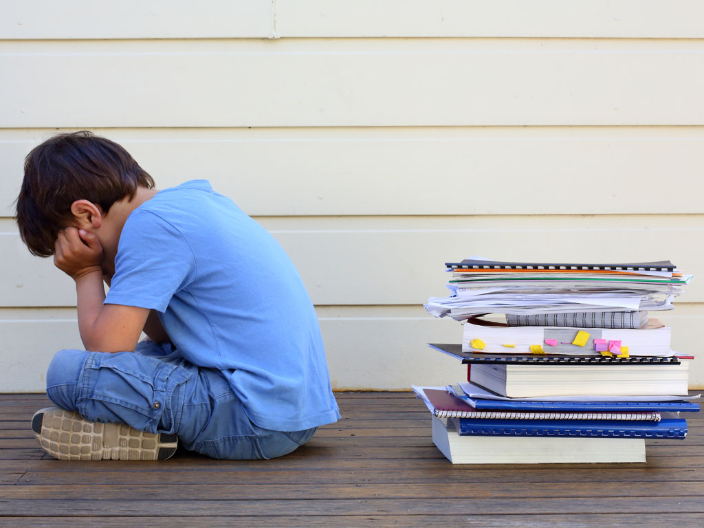 young boy crying and overwhelmed by school work