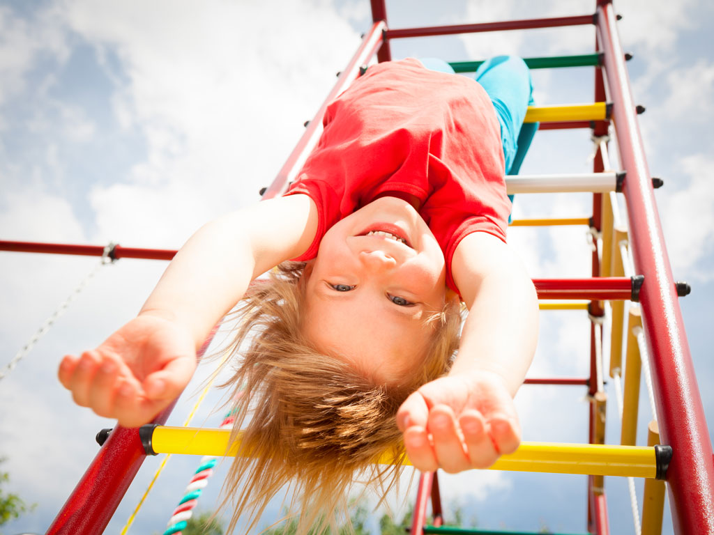child having fun hanging upside down on playground