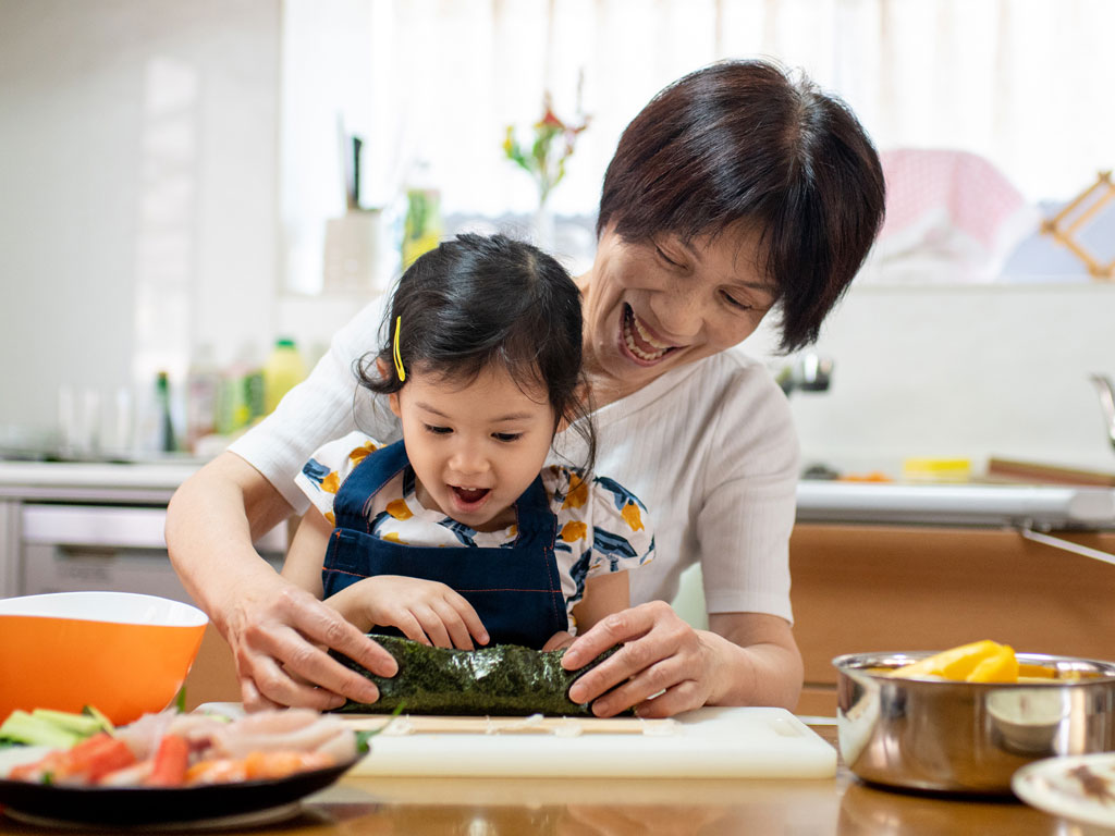 mom making sushi with her young daughter