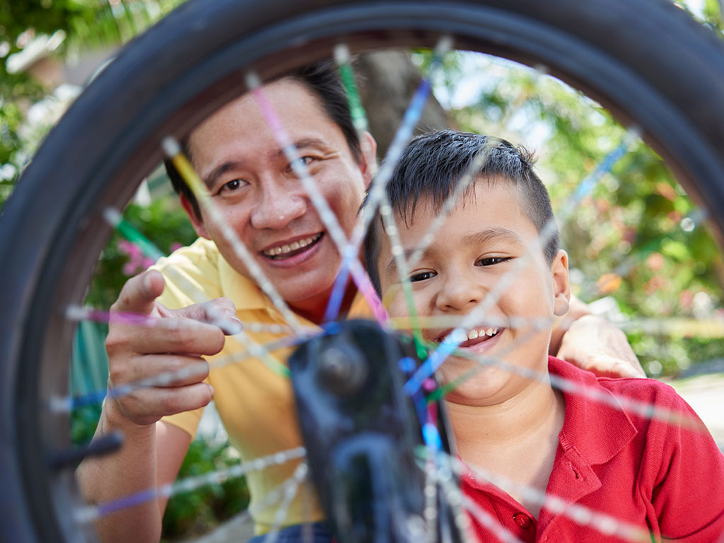 dad and young son fixing a bicycle wheel