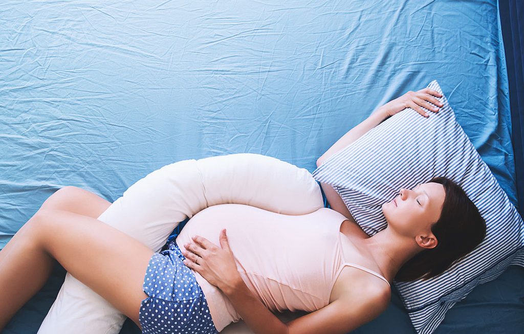 pregnant woman relaxing with a maternity pillow