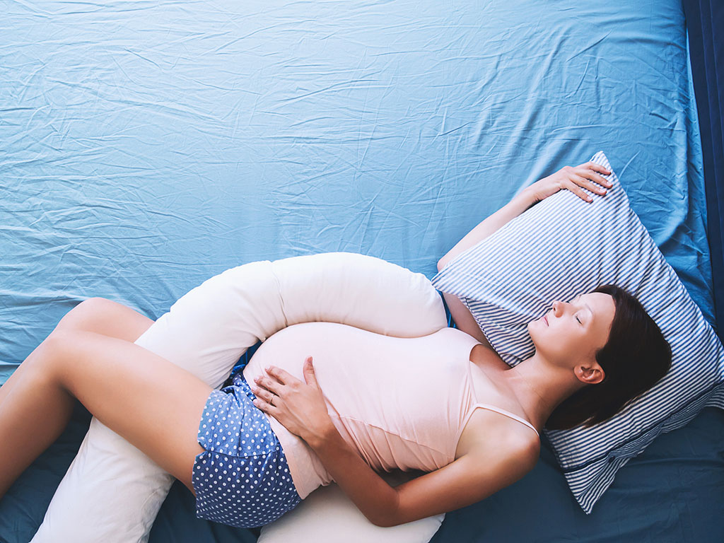 pregnant woman relaxing with a maternity pillow