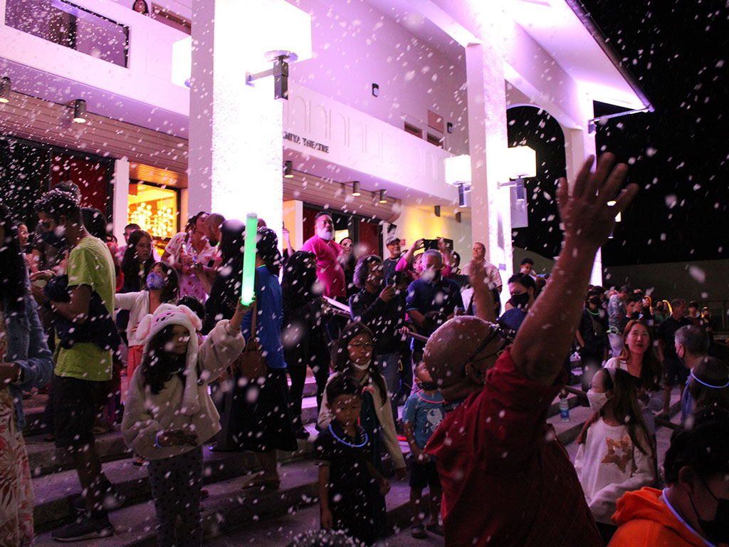 families enjoying snow during Mo`olelo Studios' Christmas Spectacular