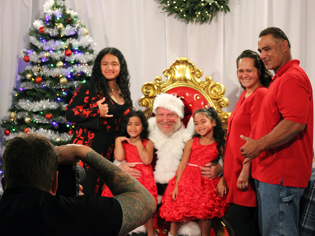 family of five taking a photo with Santa Claus at Mo`olelo Studios' Christmas Spectacular