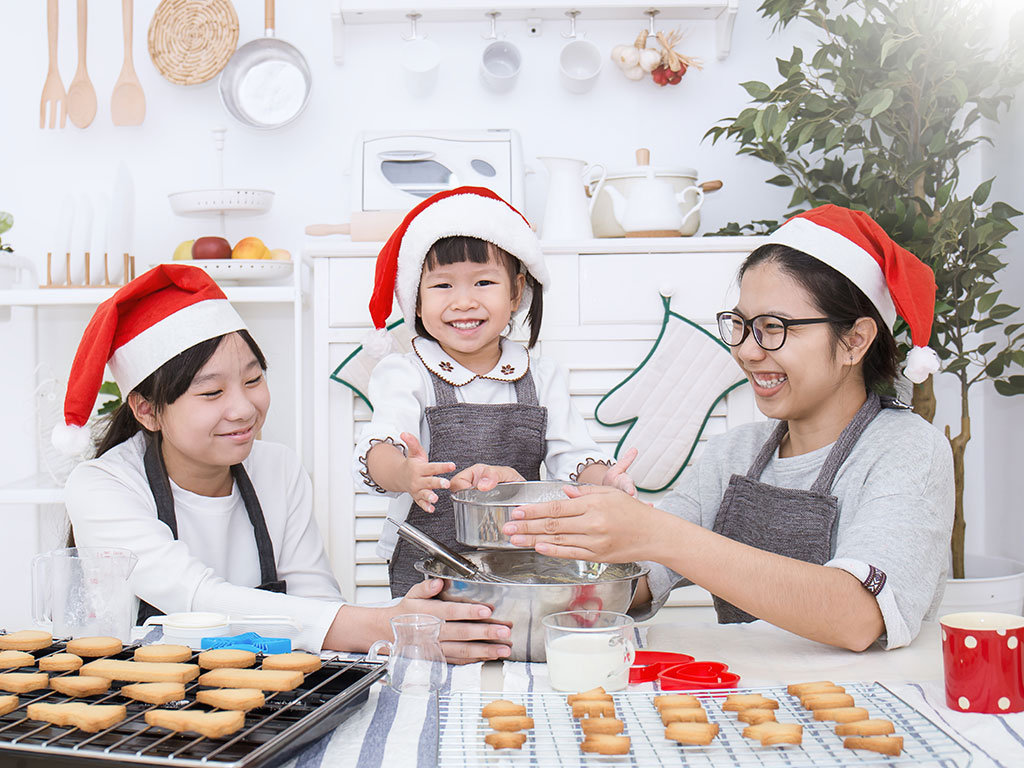 a family of three making holiday cookies