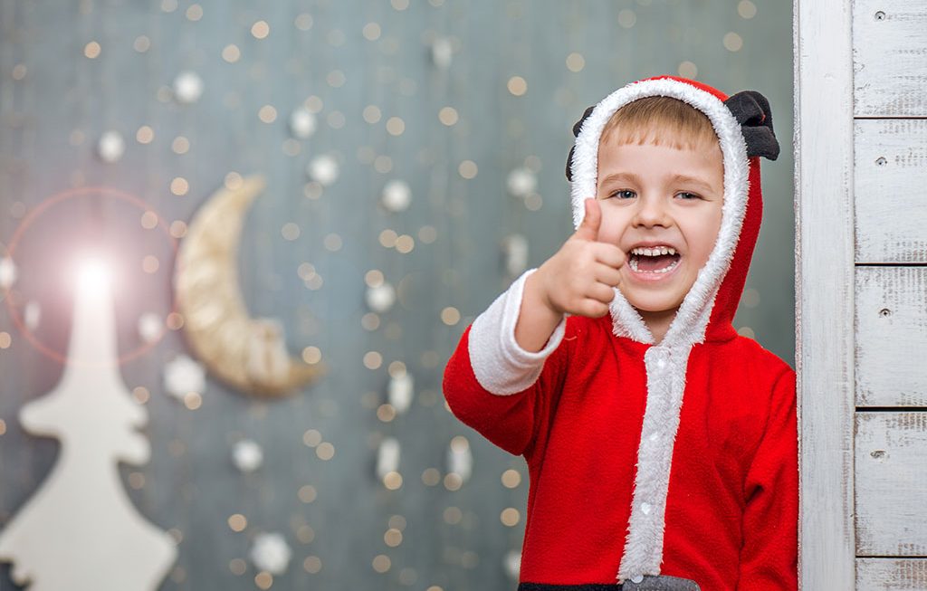 a young boy in a Santa costume with his thumb up