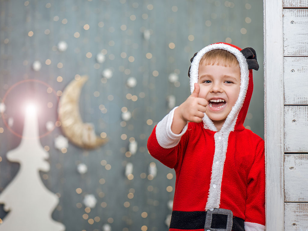 a young boy in a Santa costume with his thumb up