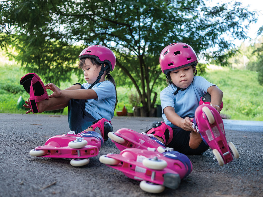 two girls carefully putting on their roller blades