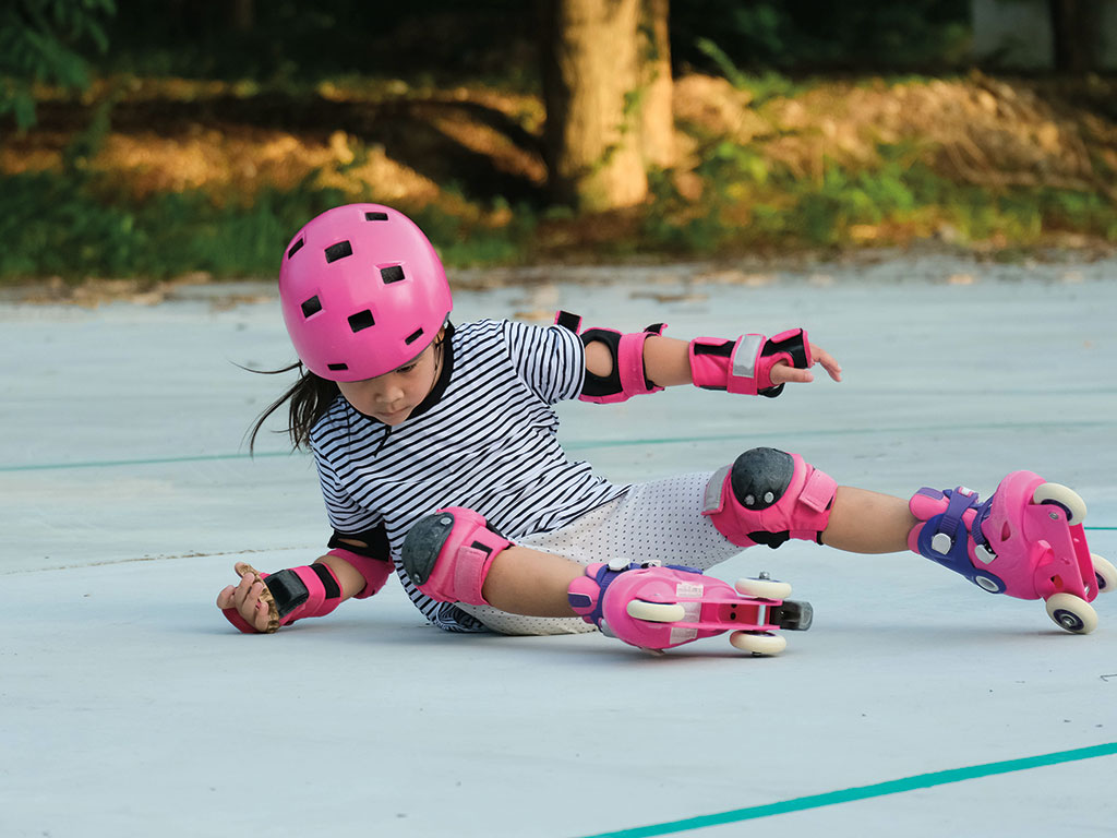 a girl in protective gear who has fallen down after roller blading