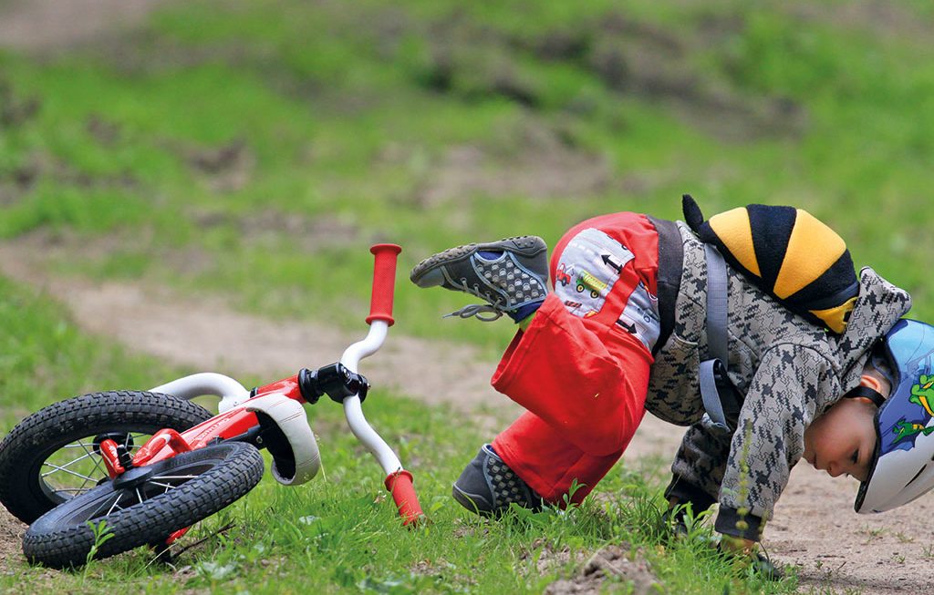a young boy in protective gear who has fallen off his bike