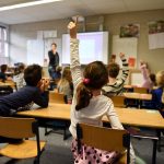 child raising her hand in a classroom
