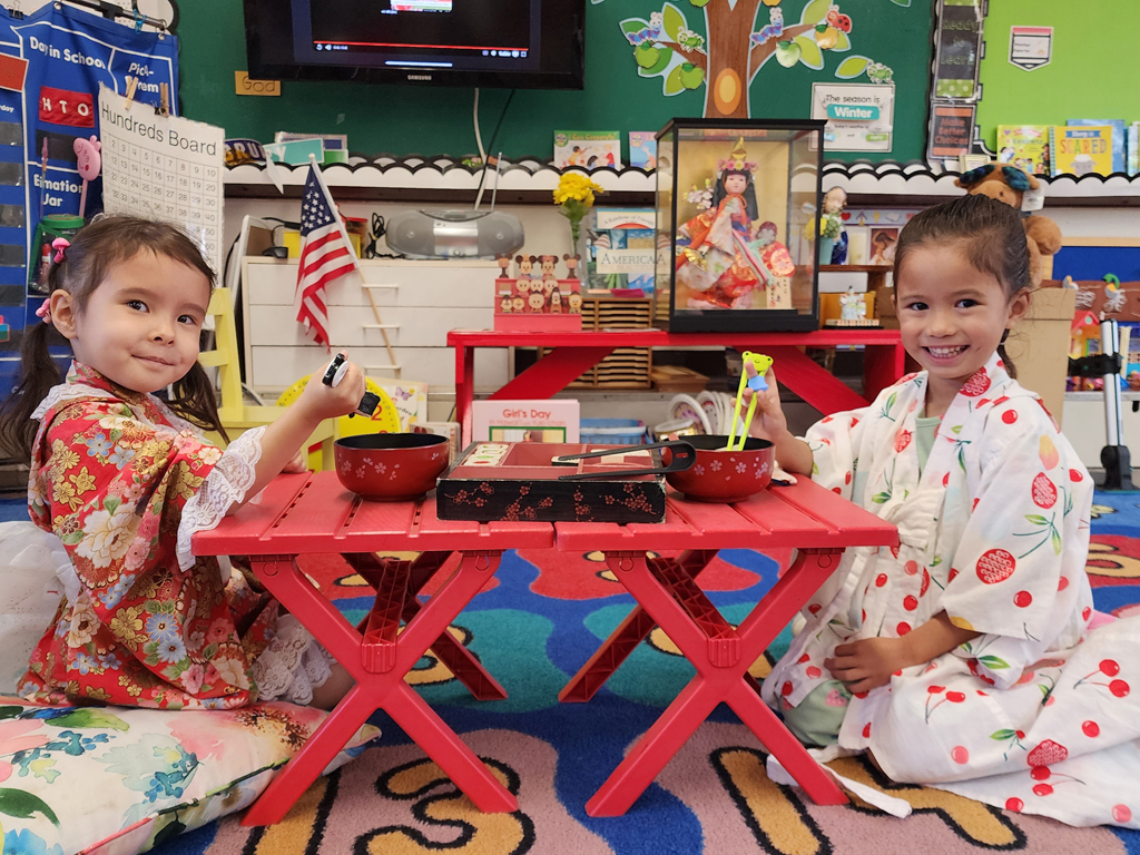 two young children sitting cross-legged on the floor wearing yukatas