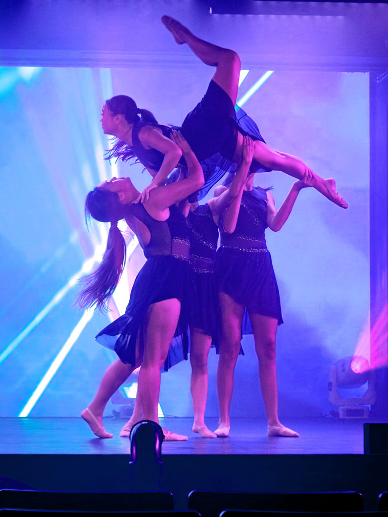 a group of females holding up fellow performer on stage