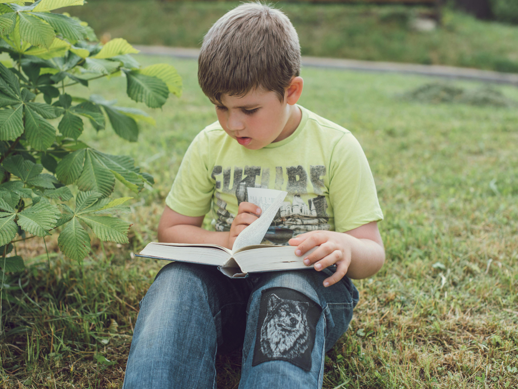 boy reading a book outdoors
