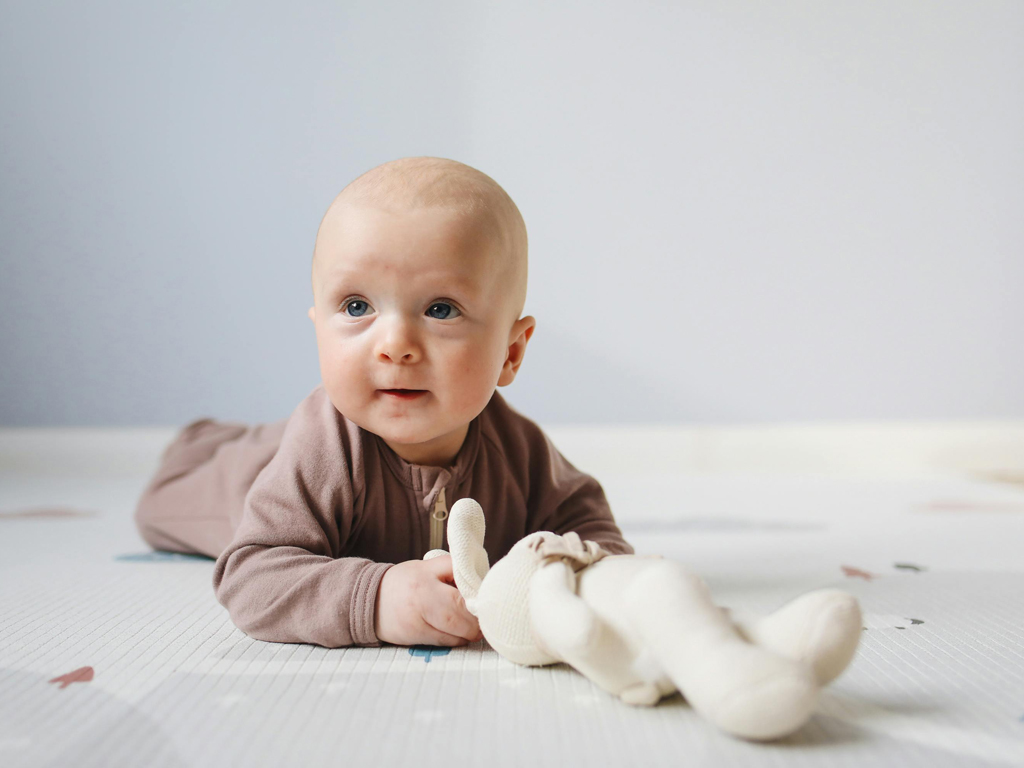 baby on their tummy with a stuffed animal