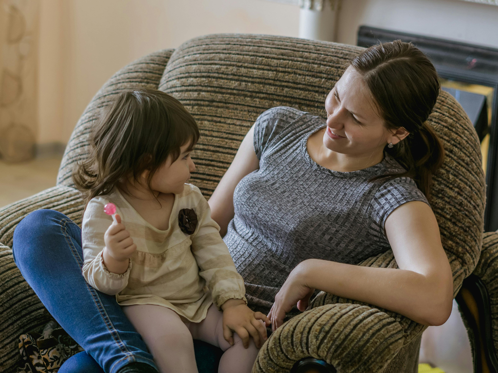 toddler holding lollipop while sitting on her mother's lap