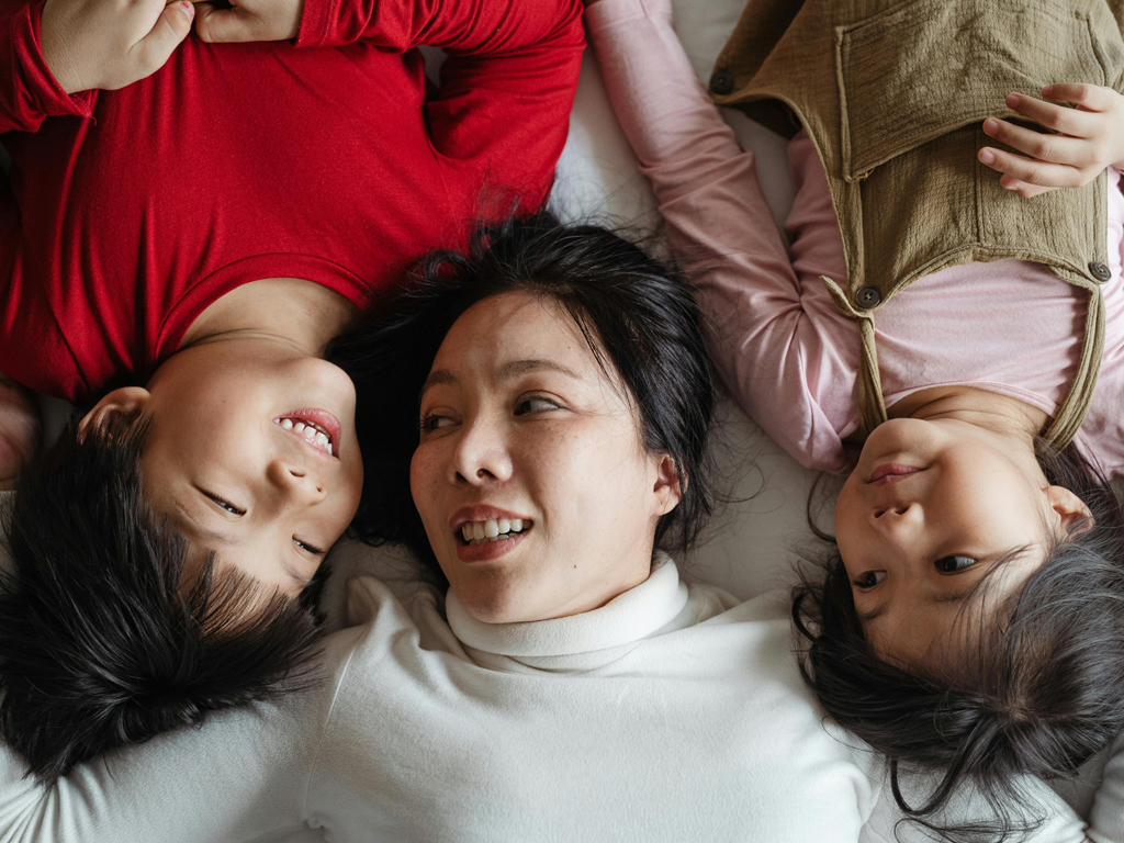 mom lying on a bed with her son and daughter