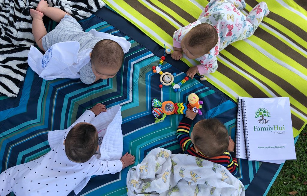 babies on their tummies on a picnic blanket outside