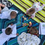 babies on their tummies on a picnic blanket outside