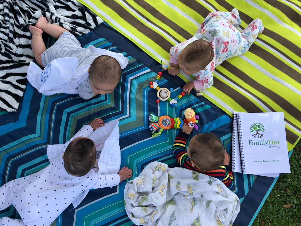 babies on their tummies on a picnic blanket outside