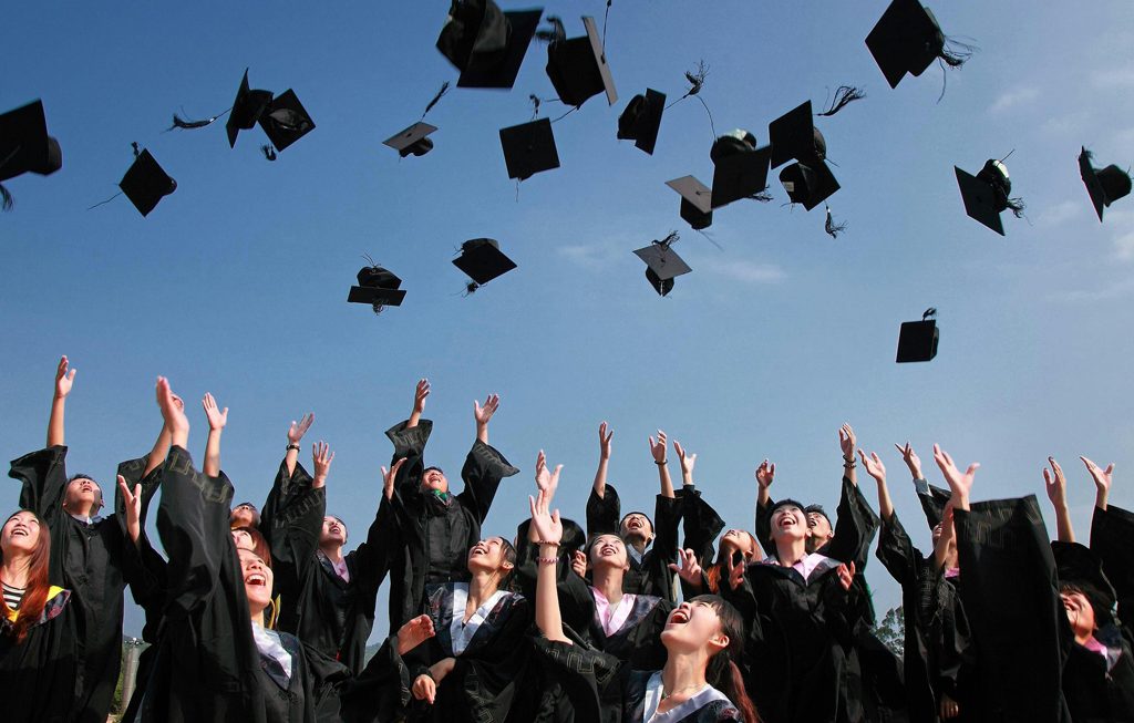 students at commencement throwing their caps in the air