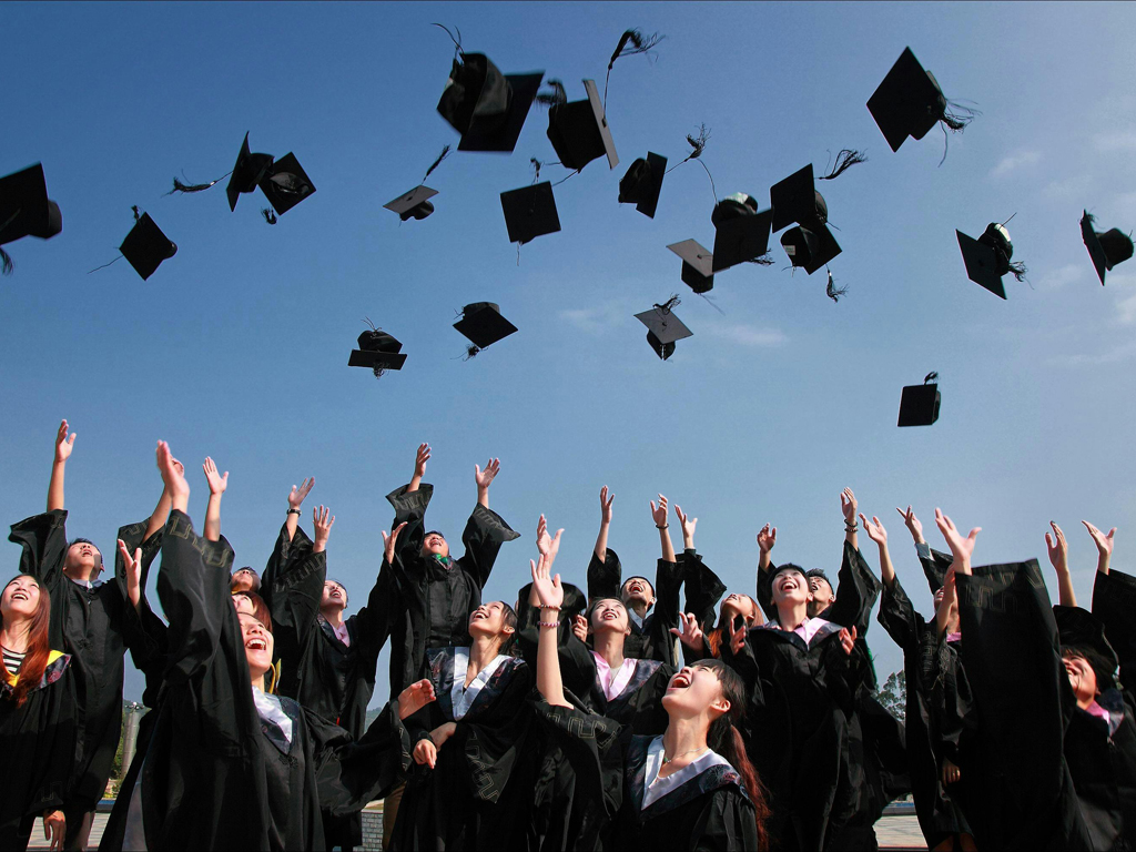 students at commencement throwing their caps in the air