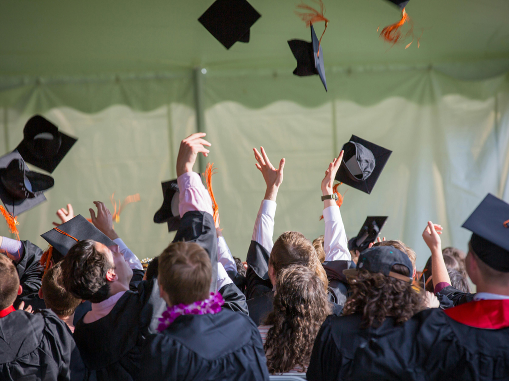 students at commencement throwing their caps in the air