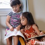 two girls sharing a chair and learning how to read