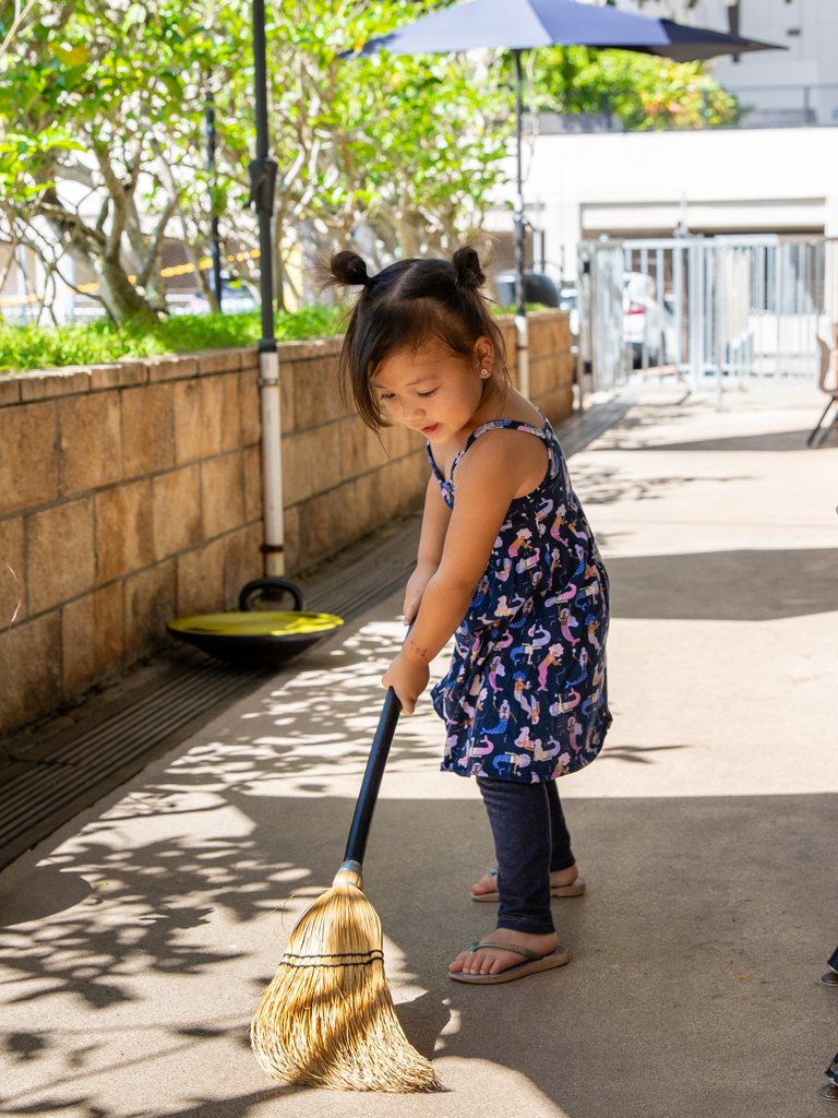 young girl learning how to sweep