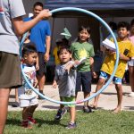 child throwing paper airplane through hula hoop at Leeward Discovery Fair