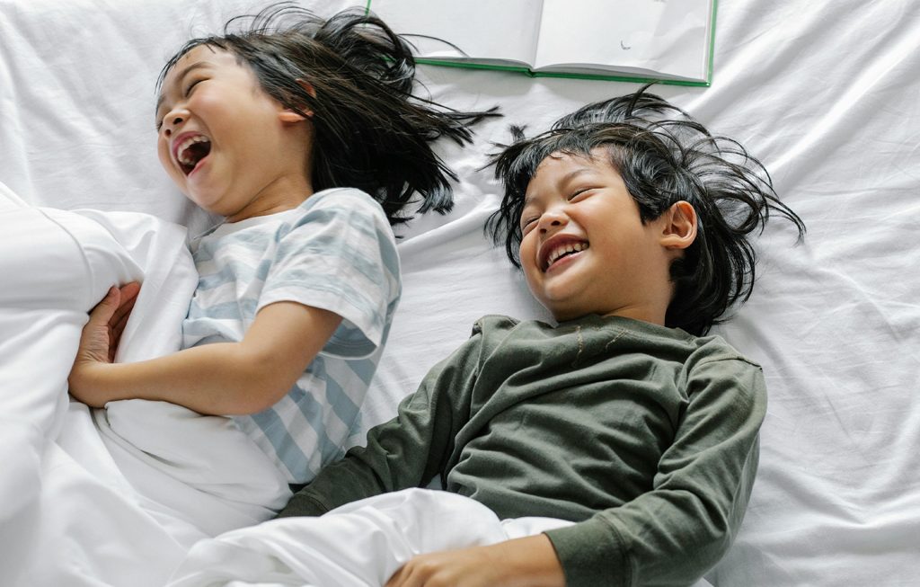 two kids laughing in bed