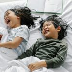 two kids laughing in bed